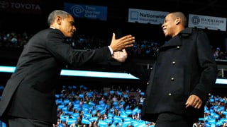 Obama und Jay-Z reichen sich auf der Bühne die Hand. 