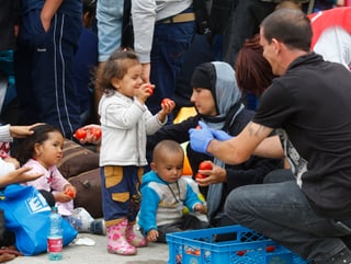 Helfer verteilt Äpfel an Flüchtlingskinder. 