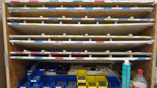 Holzgestell mit verschiedenen Schrauben und andern Metallteilen in Plastikbehältern. Holzgestell mit verschiedenen Schrauben und andern Metallteilen in Plastikbehältern.