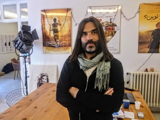 Khaled Mouzanar in seinem Büro, hinter ihm Filmplakate. Khaled Mouzanar in seinem Büro, hinter ihm Filmplakate.