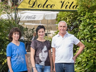 Eine ältere und eine jüngere Frau und ein Mann stehen vor dem Eingang eines italienischen Restaurants.