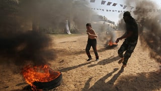 Ein Jugendlicher und ein Kind rennen durch Rauch und Feuer.
