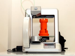 Ein 3D-Drucker mit einem gedruckten roten Turm aus Plastik.