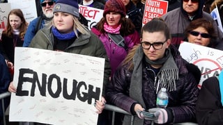 Protestierende Schülerinnen, eine von ihnen hält ein Plakat mit der Aufschrift "Enough" vor sich hin.