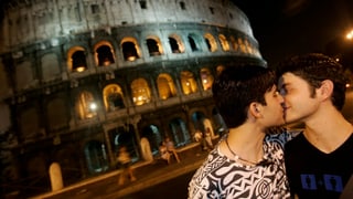 Zwei Männer küssen sich vor dem Kolosseum in Rom.