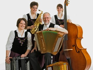Drei Musikantinnen und ein Musikant mit ihren Instrumenten auf einem Gruppenbild.