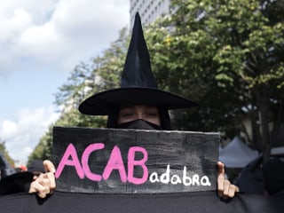 Eine Demonstrantin geht auf die Strasse als Hexe verkleidet.