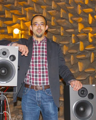 Ein Portrait von Ercan Altinsoy, der zwischen zwei Lautsprechern steht.