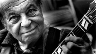 Schwarzweissfoto eines Mannes mit Gitarre.