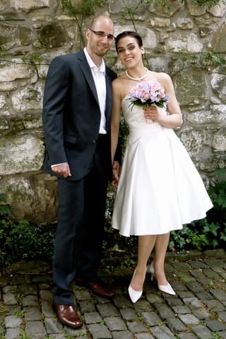 Stefan Schwitter im Anzug und Nina Burri in einem kurzen, weissen Hochzeitskleid.