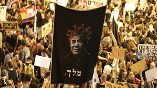 Protestierende halten ein hämisches Netanjahu-Banner hoch. Protestierende halten ein hämisches Netanjahu-Banner hoch.