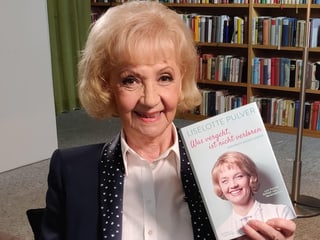 Eine ältere blondhaarige Frau mit einem Buch in der Hand. Eine ältere blondhaarige Frau mit einem Buch in der Hand.