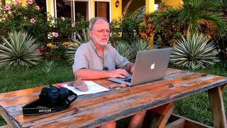 ein Mann sitzt im Garten am Laptop