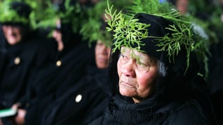 Eine ältere Frau in festlicher, Schwarzer Kleidung.