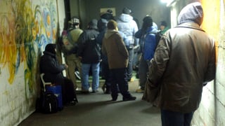 Menschen von hinten, die in einem Betongang auf ein Einlass warten. Menschen von hinten, die in einem Betongang auf ein Einlass warten.