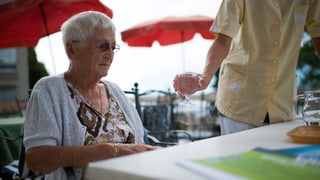 Eine ältere Dame bekommt ein Glas Wasser