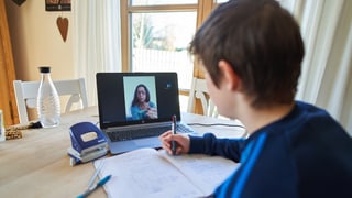 ein junger Bub erhält von seiner Lehrerin am Laptop Instruktionen