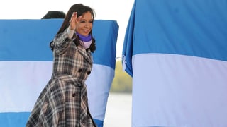 Argentiniens Präsidentin Cristina Fernandez Kirchner winkt, hinter ihr zwei aufgespannte argentinische Fahnen.