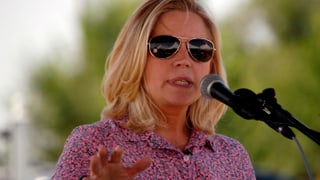Eine blonde Frau mit Sonnenbrille am Rednerpult