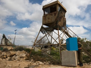 Ein Soldat gibt in einer improvisierten Wahlkabine auf einer Mauer an einem Posten in der Westbank seine Stimme ab, im Hintergrund ein Wachturm