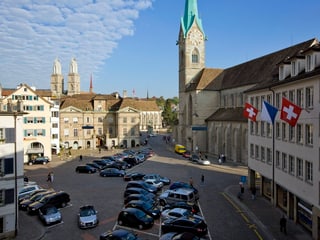 Der Platz «Münsterhof» unter blauem Himmel mit zahlreichen parkierten Autos.