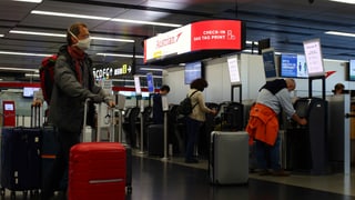 Passagiere mit Schutzmaske checken am Flughafen Wien ein.