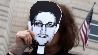 Eine Frau hält ein Snowden-Bild vor ihr Gesicht