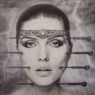 Zu sehen ist die Sängerin Debbie Harry. Vier grosse Nadeln durchboren ihr Gesicht. Abgesehen von den Nadeln sieht sie makellos aus.