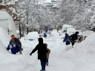 Tief verschneites St. Gallen und Menschen beim Schneeschaufeln.