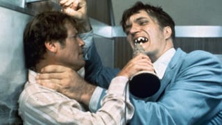 Zwei Männer kämpfen. Einer davon versucht, den anderen mit seinen Zähnen aus Metall zu beissen.