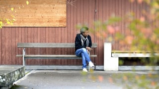 Symbolbild Asylunterkunft. Ein Mann sitz vor einer Asylunterkunft auf einer Bank. 