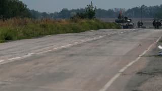 Leere Strasse in Nahaufnahme, im Hintergrund klein ein Panzer der pro-russischen Rebellen
