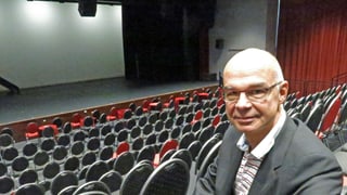 Mann sitzt in einem leeren Saal mit Bühne