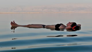 Eine Frau liegt auf dem Rücken auf dem Toten Meer. 