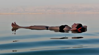 Eine Frau liegt auf dem Rücken auf dem Toten Meer. 