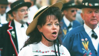 Eine Frau in Schweizer Tracht singt. 