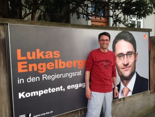 Lukas Engelberger im Joggingdress vor eigenem Wahlplakat