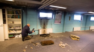 Polizeimitarbeiter fotografiert angebrannte Wand
