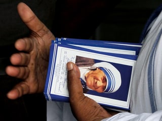 Eine Hand hält Karten mit dem Bild Mutter Teresas.