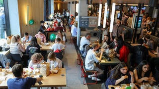 Menschen sitzen und essen in einem Fast-Food-Lokal. 
