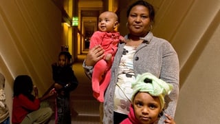 Eine Mutter steht mit ihren Kindern in einem Hotelflur Eine Mutter steht mit ihren Kindern in einem Hotelflur