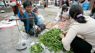 Auf einem Markt werden grüne Chilischoten gewogen.