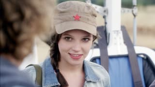 Eine junge Fraum mit einer Mütze mit einem Stern drauf, sie trägt eine Jeansjacke.