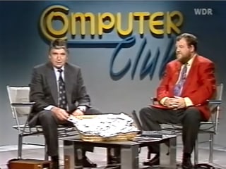 Zwei Männer sitzen auf Stühlen, in der Mitte einen Tisch - der Computerclub des WDRs 1994.