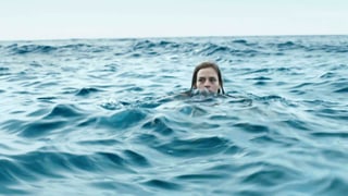 Ein junges Mädchen im Meer. Man sieht nur ihren Kopf aus dem Waser ragen. 
