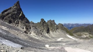 Blick in eine steinige Berglandschaft. Im Vordergrund kleinere Eisfelder