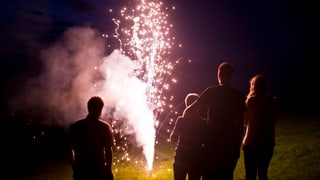 Ein Vulkan spuckt Feuer, vier Zuschauer stehen davor und geniessen den Anblick