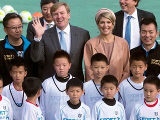 Máxima und Willem-Alexander bei einer Gruppenaufnahme mit chinesischen Kindern.