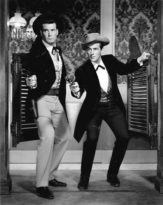 Zwei Western-Figuren stehen in einer Saloon-Türe und zücken je eine Pistole