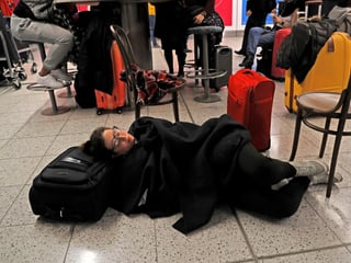 Eine Frau liegt am Boden auf ihrem Koffer.